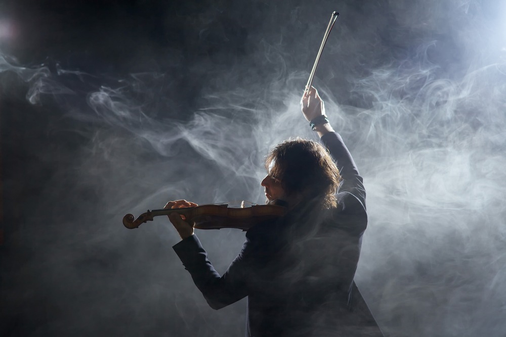 How to Play Fast on the Violin - a man lifting the violin bow in smoke