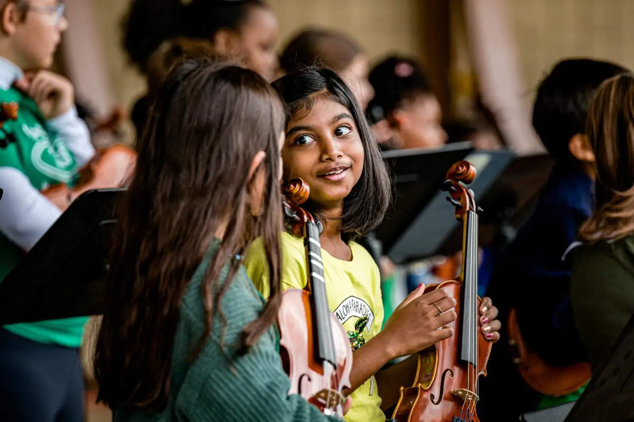 Young violin players talking while holding their violins