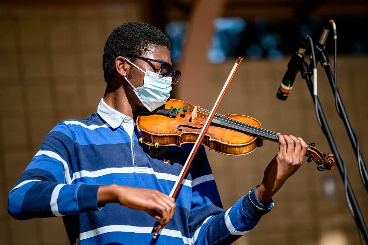 Young violinist wearing a face mask performing outdoors