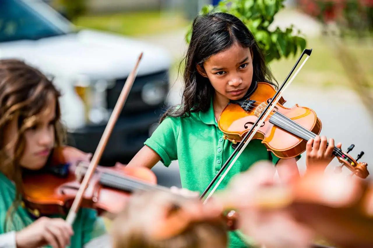 Young violinists playing together outdoors